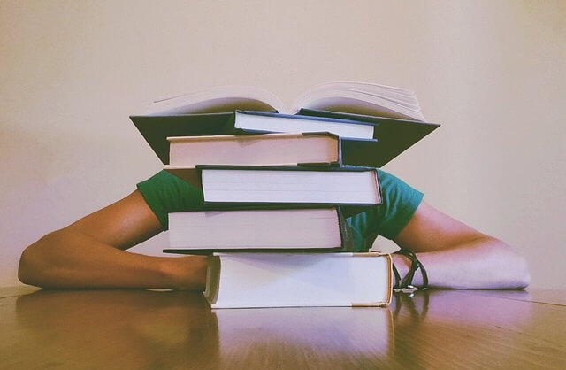 Student chowający się za stertą książek