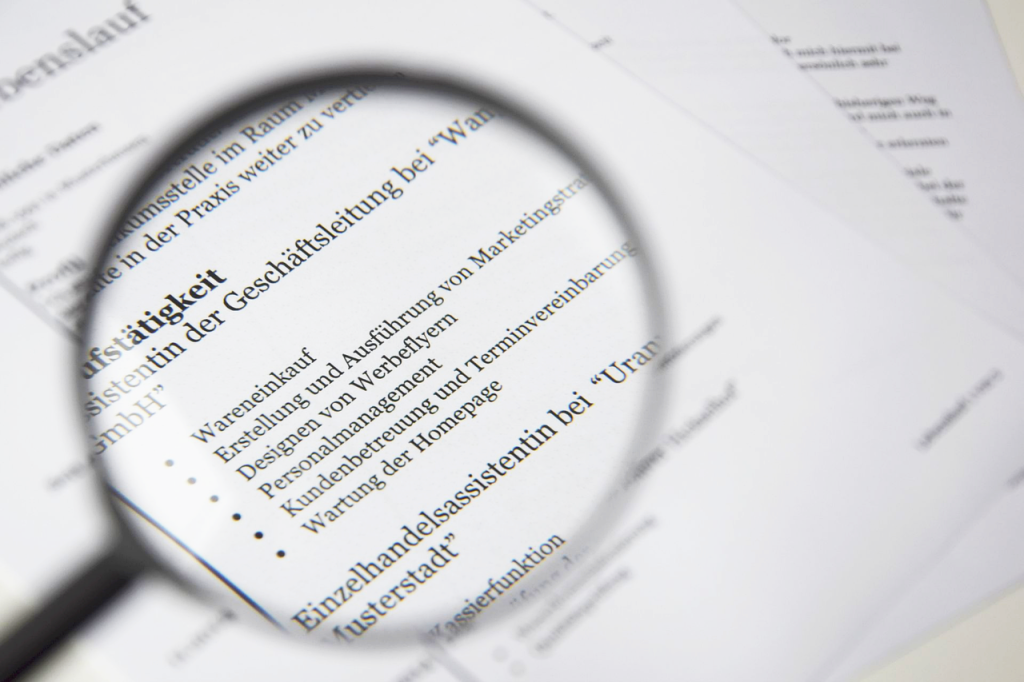 Dokument CV oglądany przez szkło powiększające podczas analizy aplikacji o pracę