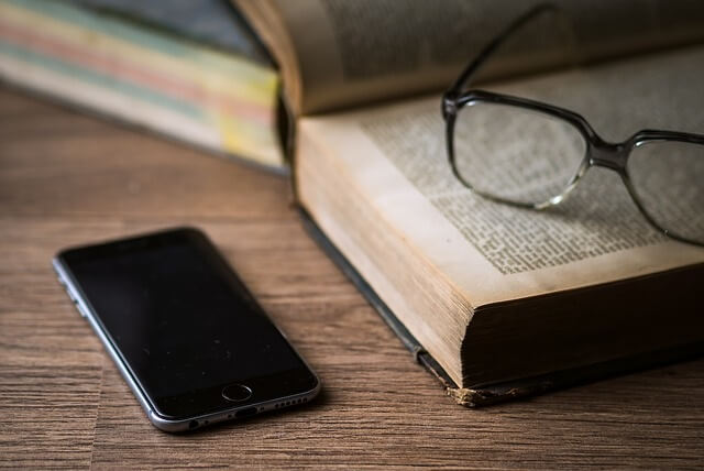 Książka, okulary i telefon leżące na stole